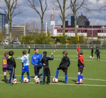 Vrijwilliger geeft voetbaltraining aan groep kinderen.
